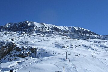 A snowy mountain with ski lifts going up it