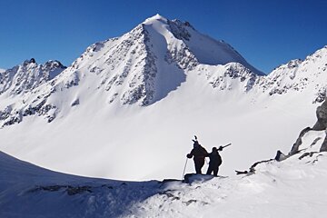 an image of two men hiking with skis on shoulders