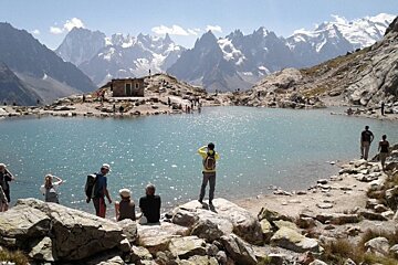 image of a lake up the mountain with people around taking photos and admiring the surrounding mountain view