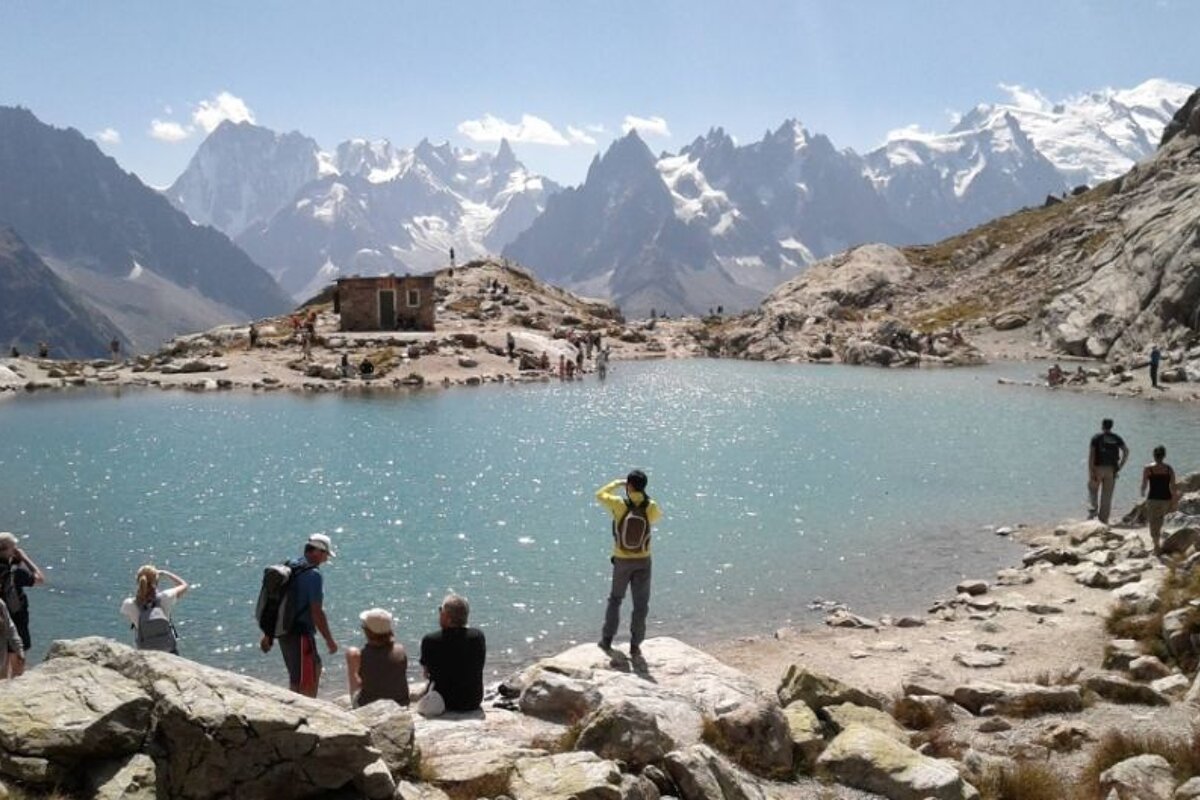 image of a lake up the moutnain with people taking photos and admiring the view of the mountains surrounding the lake