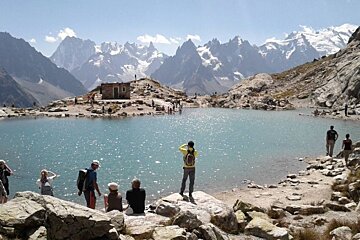 image of a lake up the moutnain with people taking photos and admiring the view of the mountains surrounding the lake