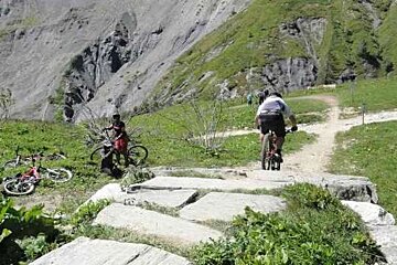 A man is riding a bike on a trail in the mountains