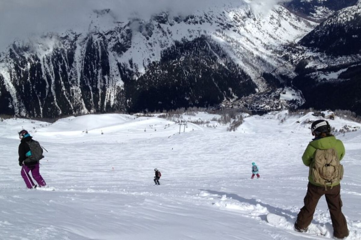 image some skiiers and snowboarders skiing off piste on fresh snow with the valley below and cloudy skies