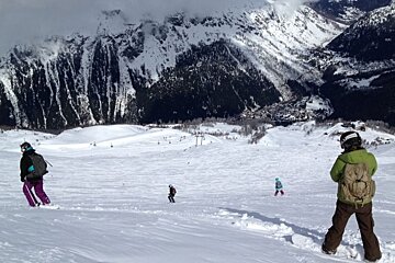 image some skiiers and snowboarders skiing off piste on fresh snow with the valley below and cloudy skies