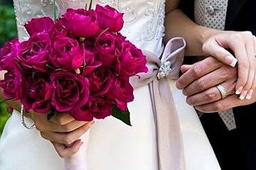 a picture of a bride holding a bunch of roses and holding hands