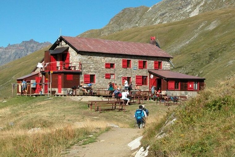 a picture of a mountain restaurant with red shutters on the windows