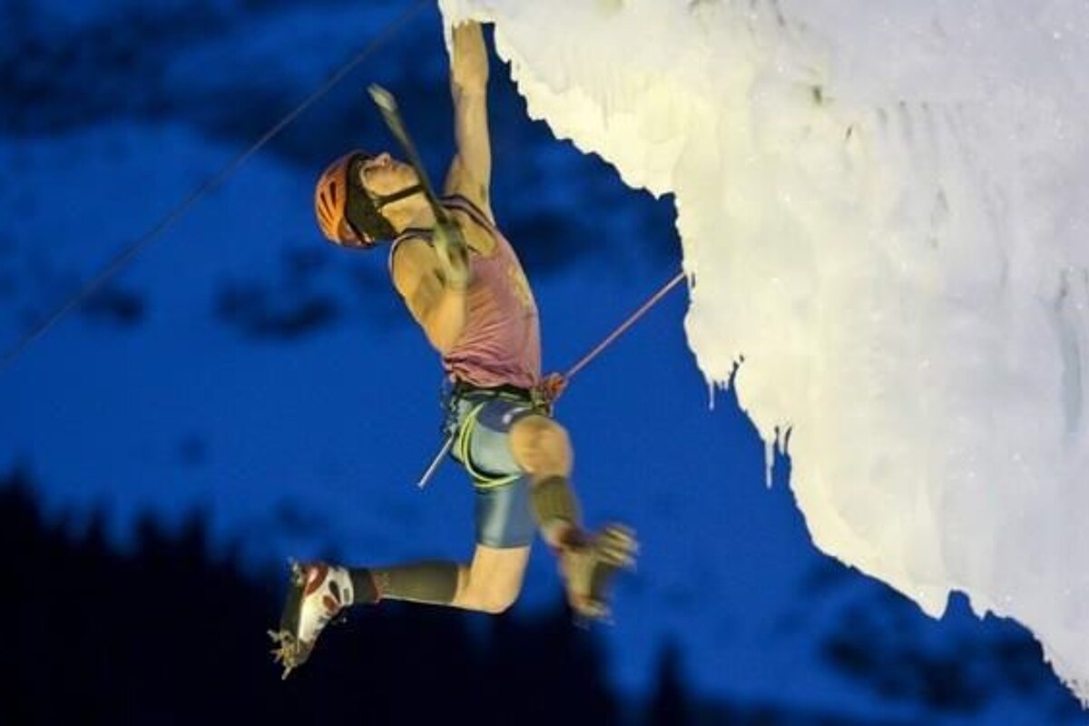 A man is climbing a large ice wall at night
