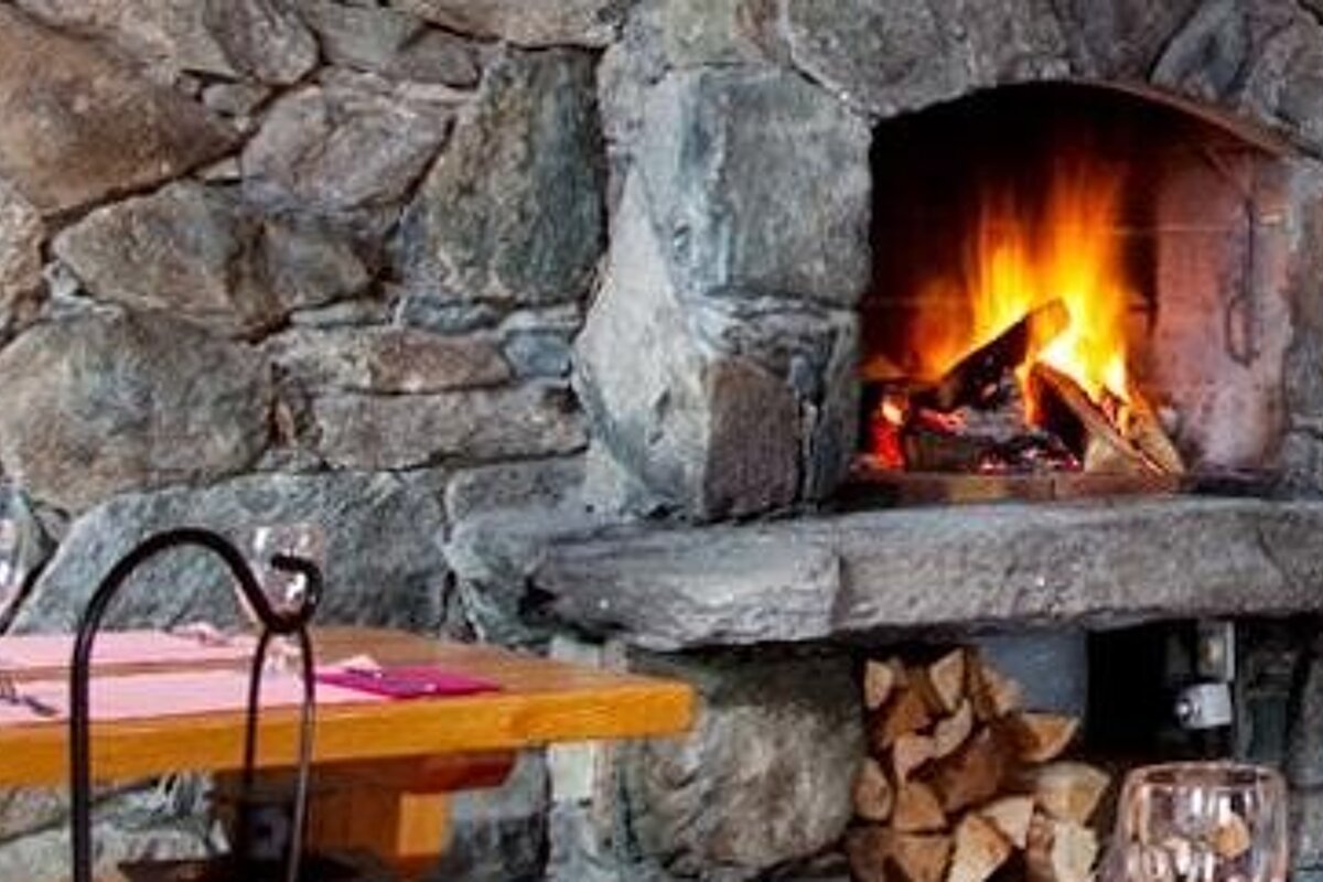 image of a stone fireplace in a restaurant with a table laid and set up on the side.