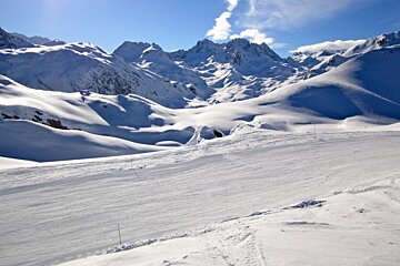 A snowy mountain landscape with a yellow pole in the foreground