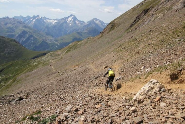 a picture of a mountain biker on a rocky trail in alpe dhuez