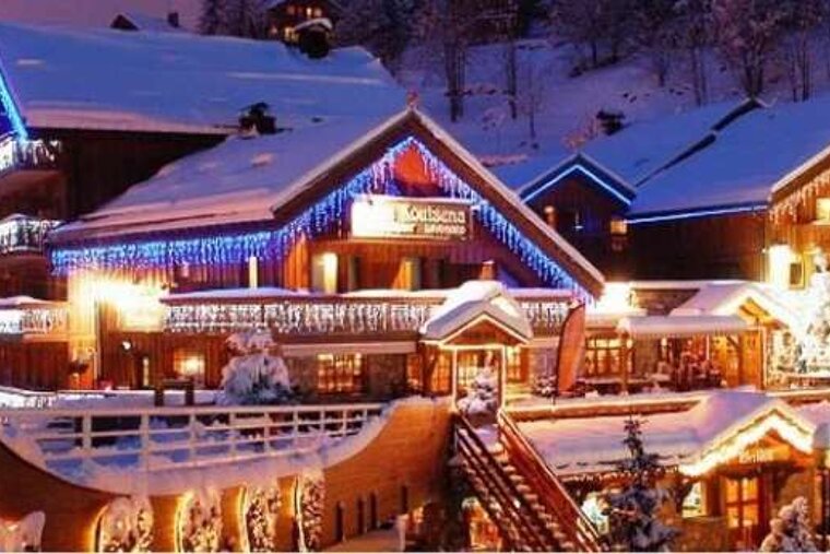 an image of a ski resort centre with lots of shops lit at night