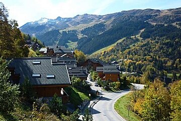image of some chalets in the mountains in the summer with the green mountains in the background