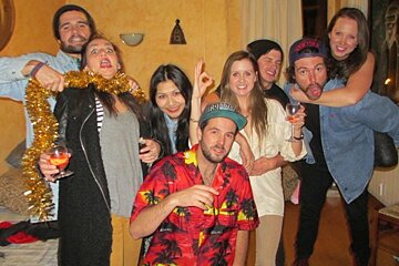 A group of people posing for a picture with one wearing a hat that says hawaiian