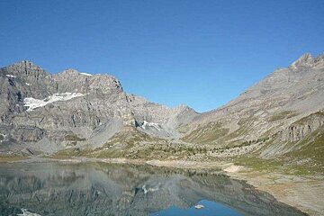 There is a lake in the middle of the mountains with mountains in the background