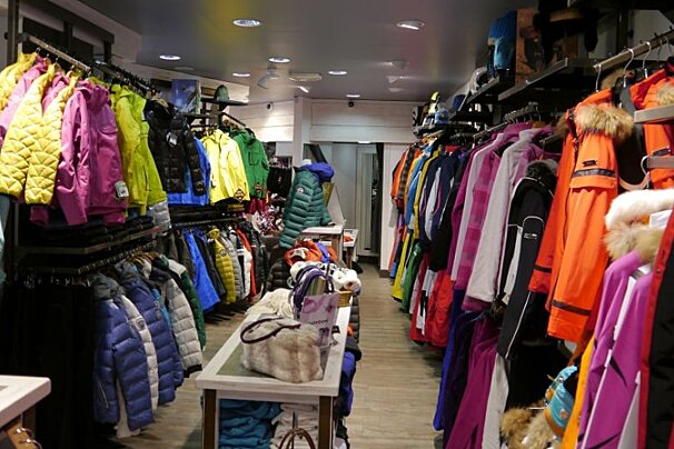 The inside of a clothing store filled with jackets and coats