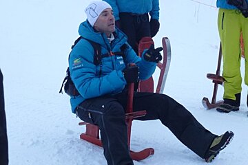 a picture of a man on a sledge in a blue jacket