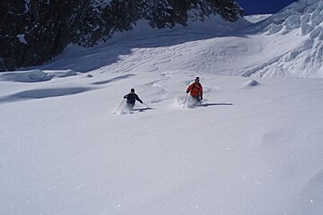 a picture of a couple of skiers leaving tracks in deep snow