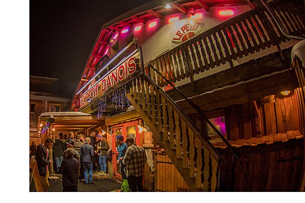 An image of a skier jumping off a snow covered chalet at a ski resort restaurant apres-ski bar in Val d'Isere