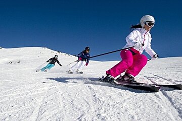 an image of three skiers carving on a piste