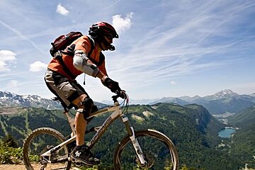 a picture of a man mountain biking with lake montriond behind