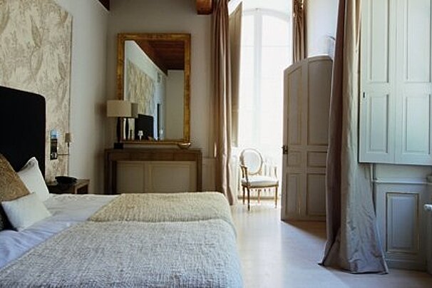 Double room with cream furnishings and mirror and cream chair