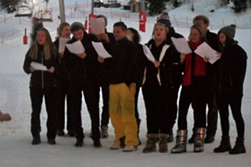 a picture of a group of carol singers in the snow