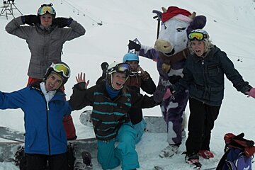 a picture of a bunch of skiers and someone dressed as the milka cow