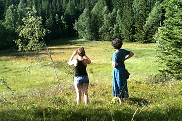 Two women standing in a grassy field looking at trees