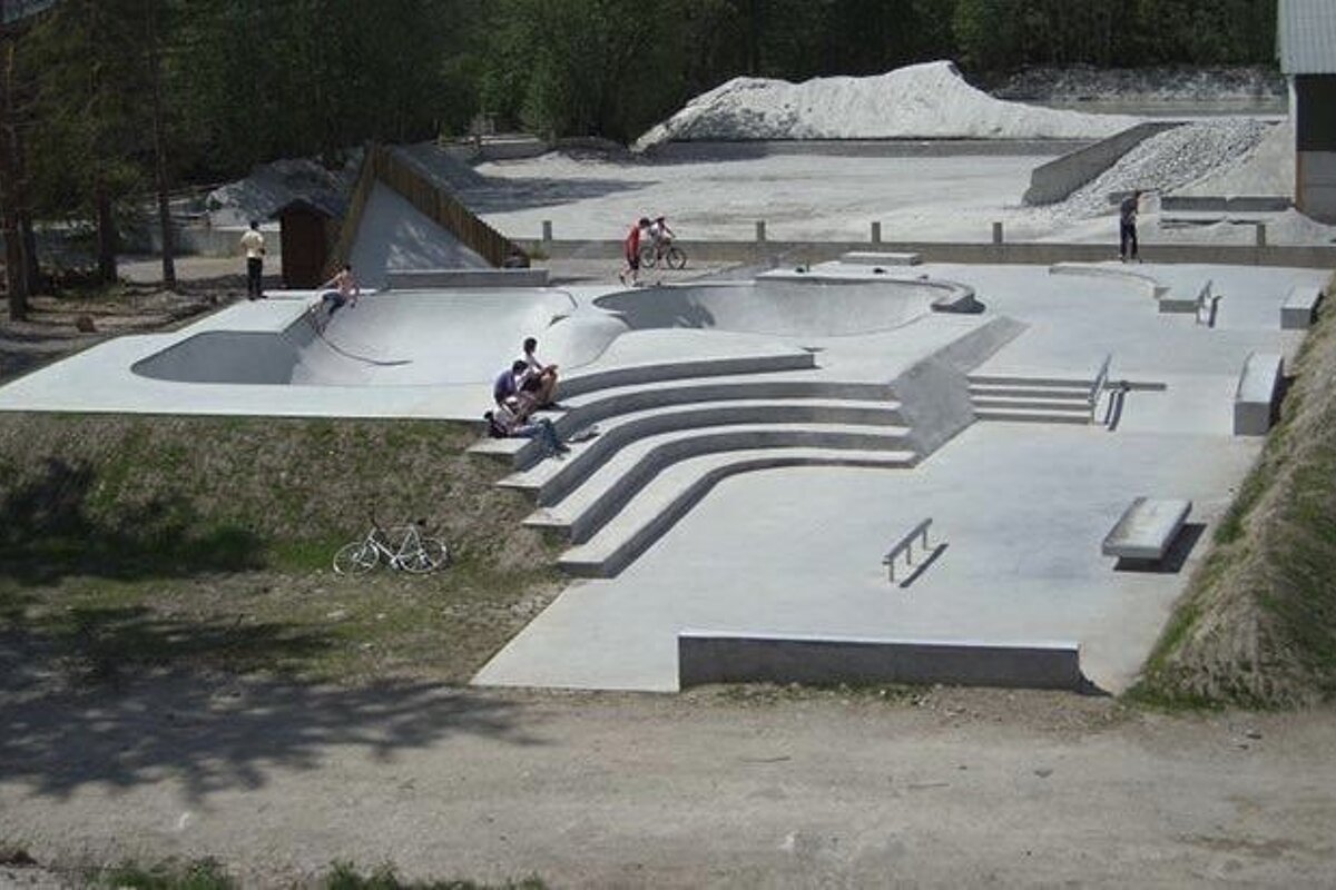 A group of people are sitting on the steps of a skate park
