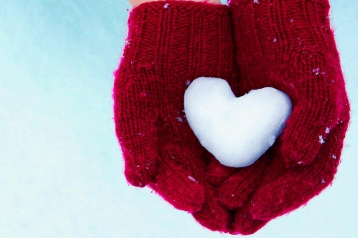 an image of a person with red gloves holding a snow heart