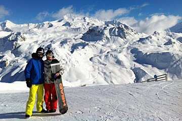 an image of snowboarders with mountains in the background