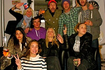 A group of people posing for a picture with a dartboard in the background