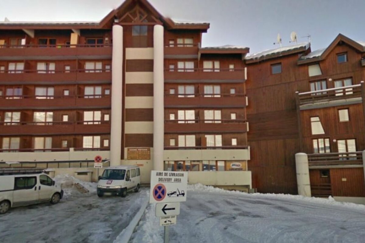 image of a large apartment block/building with cars parked out front and snow on the ground