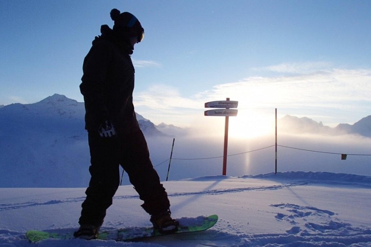 an image of a snowboarder with sun coming up