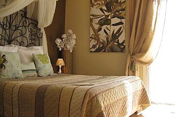 Double bed with cream wall and overhanging curtains