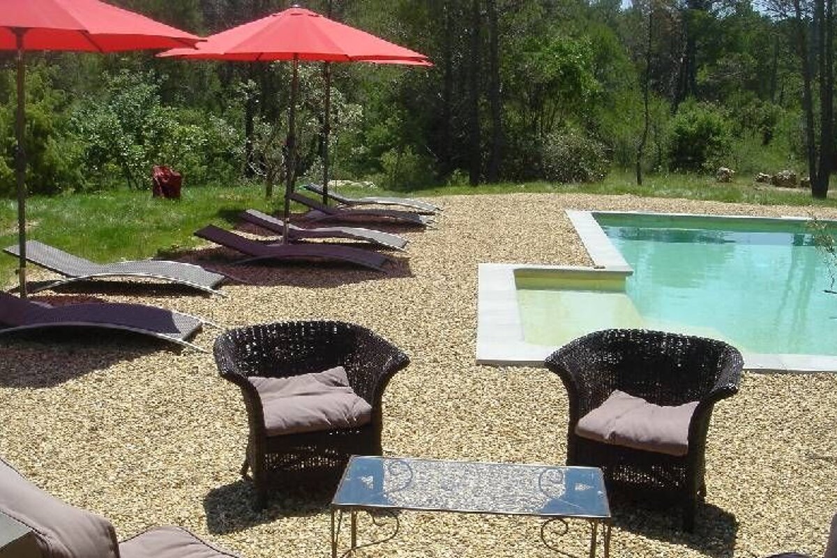 Pool with brown curved wicker sun loungers an brown wicker chairs