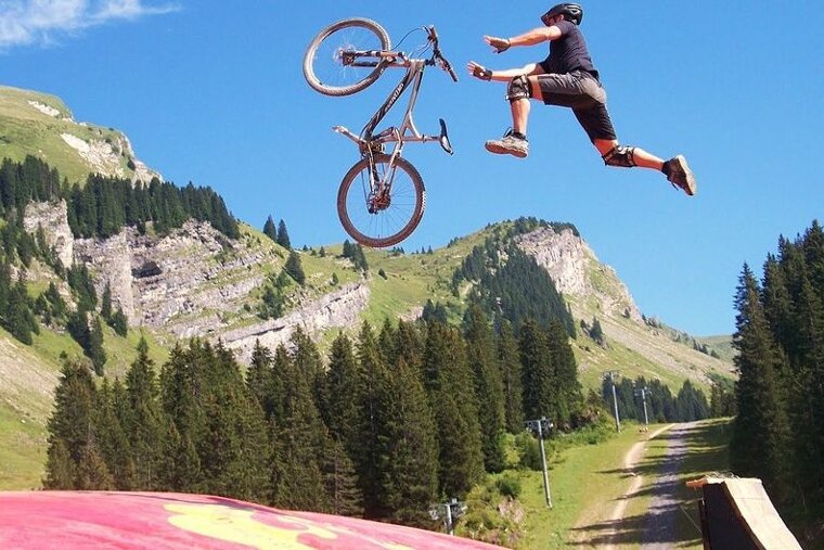 a picture of a man and his bike flying off an airbag jump