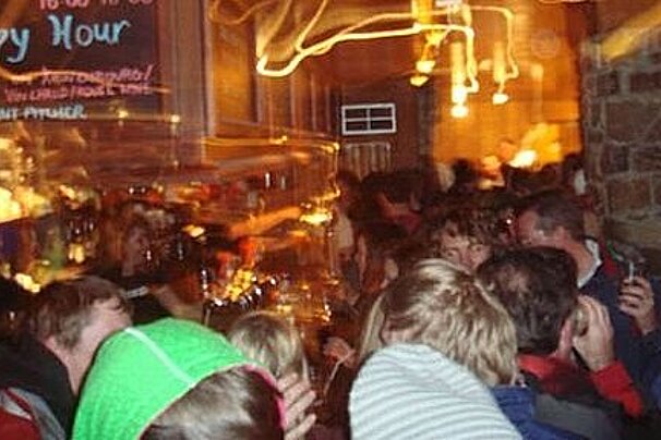 A crowd of people are gathered in a bar