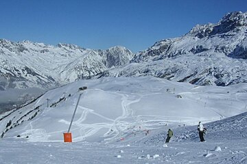 Skiers on a snowy slope with mountains in the background