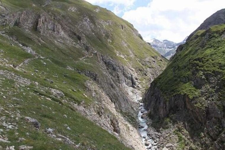 image of some grass and rock covered mountains with a small valley with a stream in
