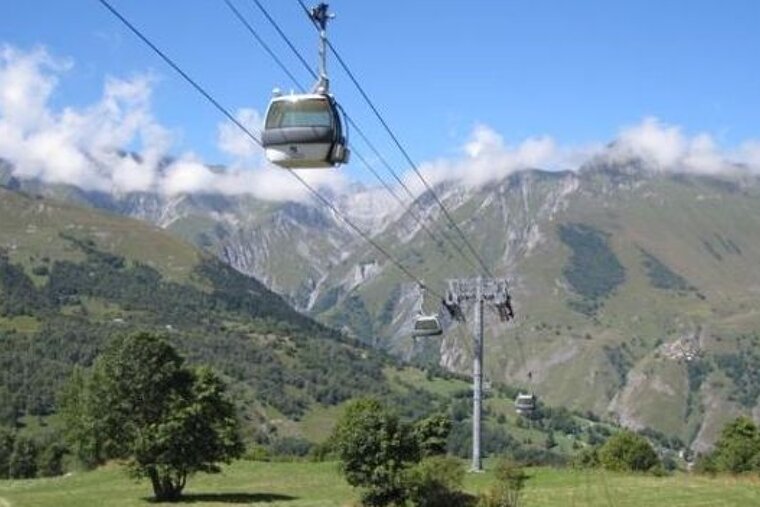 image of a bubble lift in the summer with green trees and fields below and mountains in the background