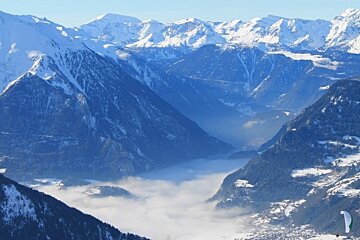 an image of verbier mountains with parapenter and inversion in the valley