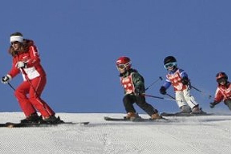 a picture of a ski instructor with a group of children following