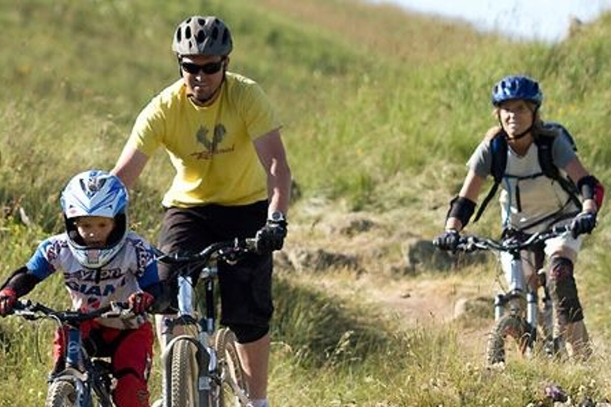 a picture of a family of three riding mountain bikes