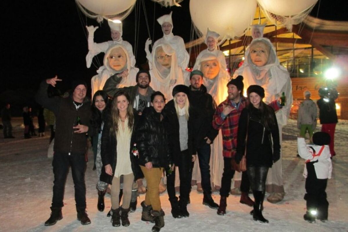 A group of people posing for a picture in front of balloons with faces on them
