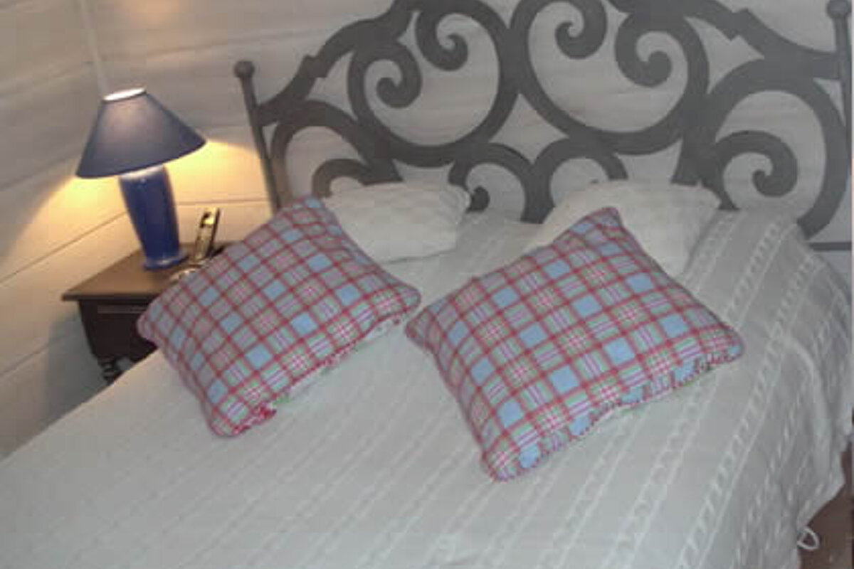 A bed with two pillows and a lamp on it