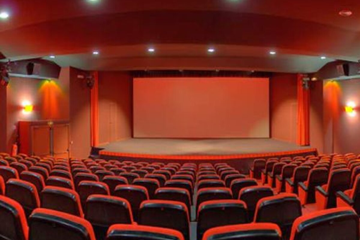 An empty auditorium with red seats and a large screen