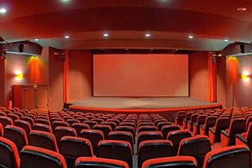 An empty auditorium with red seats and a large screen