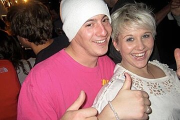 Two people in a bar giving thumbs up sign
