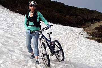 A woman wearing a helmet is riding a bike in the snow